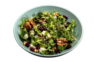 Salad with beets rucola parsley herbs feta cheese walnuts in a bowl on isolated background