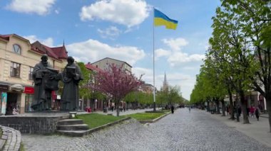 Ukrayna, Mukachevo - Mayıs 2023: Mukachevo şehrinin tarihi merkezi. Barış Meydanı 'ndaki şehir merkezinde dalgalanan ulusal bayrağıyla Cyril ve Methodius anıtı.