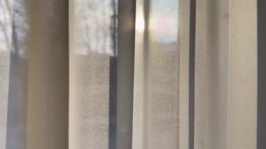 Pencere perdeleri yaz meltemiyle hareket ediyor deniz kenarındaki apartmanın penceresinden içeri doğru..