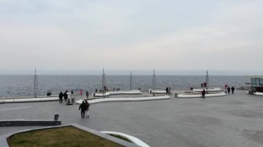 Odessa, Ukrayna - 01 Nisan 2023: İnsanlar fırtınalı havada iskelede yürüyor. Yüksek kalite 4k görüntü