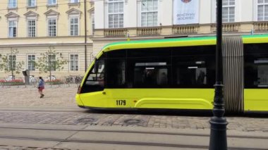 Lviv, Ukrayna - Mayıs 2023: Modern sarı tramvay şehir merkezindeki kalabalık caddeden geçiyor, toplu taşıma. Yüksek kalite 4k görüntü