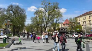 Lviv, Ukrayna - Mayıs 2023: Güneşli bir günde Opera Salonu yakınlarındaki parkta yürüyen insanlar. Yüksek kalite 4k görüntü