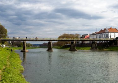 Uzh Nehri rıhtımındaki yaya köprüsü - Uzhhorod 'un ünlü turistik manzarası ve bahar günü popüler eğlence bölgesi. Yüksek kalite 4k görüntü