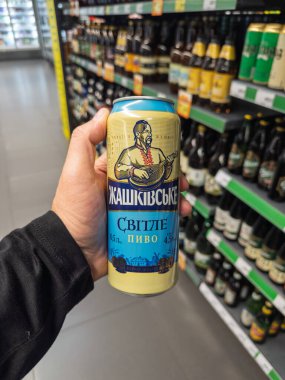 Kyiv, Ukrayna - 5 Temmuz 2025: Süpermarket bira reyonunda bir kutu Zhashkivske Svitle Ukrayna light birası tutan bir el. Yüksek kalite fotoğraf