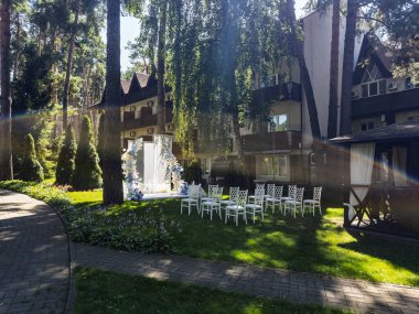 Uzun çam ağaçlarının altında huzurlu bir düğün yeri. Dekoratif kemerli boş koltuklar ve yumuşak öğleden sonra ışıkları..