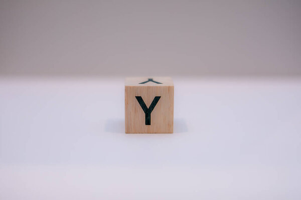 Wooden block written "Y" with a white background, education concept, close-up.
