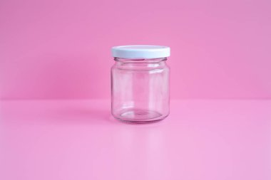 1 boş kavanoz, beyaz kapak, pembe bir sahne, yakın plan..