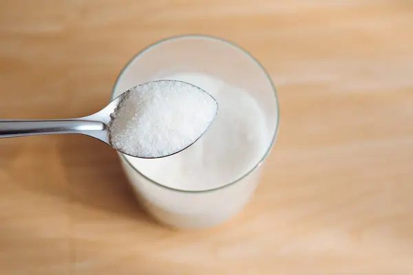 1 tablespoon sugar on a jar with a wooden background.