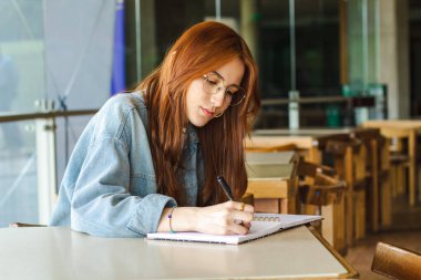 Genç ve güzel bir bayan, pencerenin yanında kitap okuyor. 