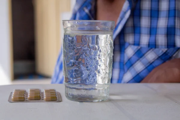 Yetişkin bir adam bir bardak suyla ilaç alıyor.