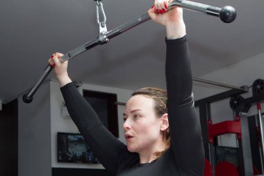 Sportif bir kadın spor salonunda ağırlıkla egzersiz yapıyor.