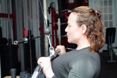 Sportif bir kadın spor salonunda ağırlıkla egzersiz yapıyor.