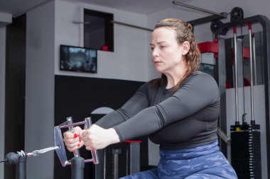 Sportif bir kadın spor salonunda ağırlıkla egzersiz yapıyor.