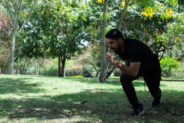 Sportif adam parkta esneme hareketleri yapıyor. Şehirdeki aktif adam eğitiminin yan görüntüsü. dinamik hareket. Spor ve sağlıklı yaşam tarzı