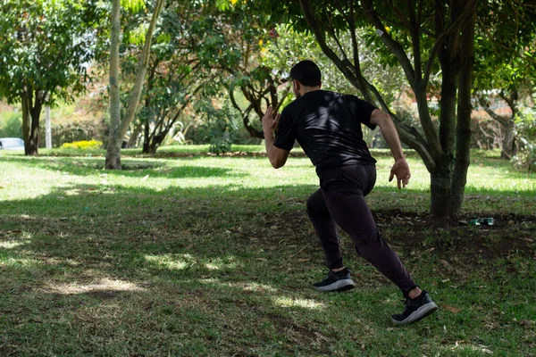 スポーティな男が走る 都市公園の森を訓練する男のリアビュー ダイナミックな動き スポーツと健康的なライフスタイル — ストック写真