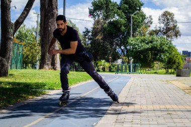 Şehirdeki bir parkta paten kayan genç bir adam.