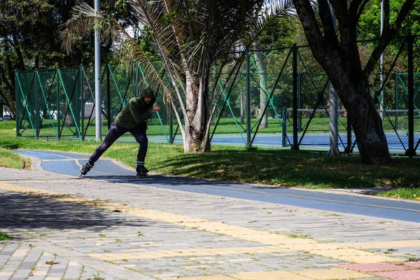 Şehirdeki bir parkta paten kayan genç bir adam.