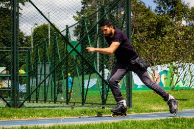 Şehirdeki bir parkta paten kayan genç bir adam.