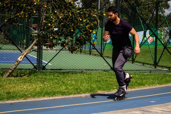 Şehirdeki bir parkta paten kayan genç bir adam.