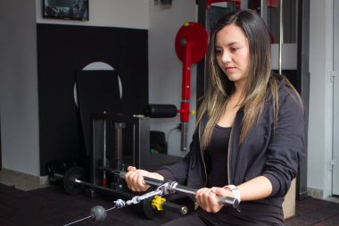 Sportif bir kadın spor salonunda kol ve omuz kasları için egzersiz yapıyor. Spor salonunda spor yapmak.