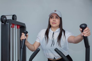 Kadın spor salonundaki bir makinede aerobik egzersizi yapıyor.