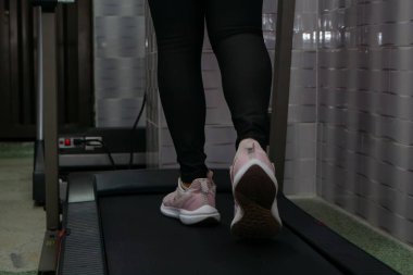 Spor makinesinde egzersiz yapan genç bir kadın.