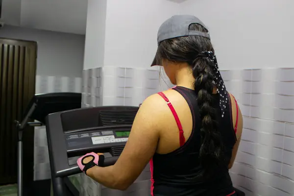 Genç kadın spor makinesinde koşu egzersizi yapıyor.