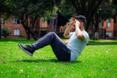 Genç fitness adamı şehirdeki bir parkta karın egzersizi yapıyor.