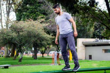 Genç jimnastikçi şehirde bir parkta fiziksel antrenman yapmak için metroda denge kuruyor.
