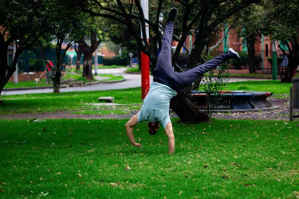 young man doing half moon break dance acrobatics in a park in the city