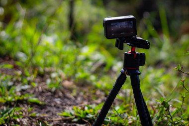 Güneşli bir günde, ormanda bir tripodun üzerinde hareket kamerası.