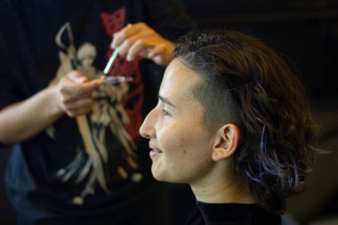 Soyunma odasında profesyonel bir makyöz tarafından makyaj yapılan genç bir kadın.