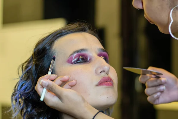 stock image young woman applying make up (paint her eyelashes) for a evening date in front of a mirror.