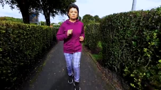 城市里的一位老年妇女早上在公园里跑步 — 图库视频影像