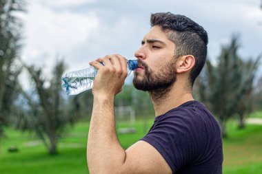 Koştuktan sonra su içen adam. Renkli Spor Giyim 'de Yakışıklı Sporcu Erkek Portresi Spor Sporundan Sonra Dinleniyor