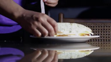 Fırıncı kadının elleri, mutfak masasında marul, jambon ve peynirli lezzetli bir sandviç hazırlıyor.