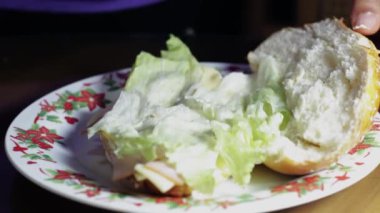 Fırıncı kadının elleri, mutfak masasında marul, jambon ve peynirli lezzetli bir sandviç hazırlıyor.