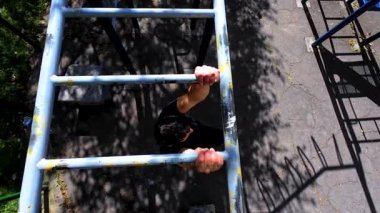 Fitness, spor, egzersiz, eğitim ve yaşam tarzı konsepti. Açık havada barfiks çeken genç bir adam. Parktaki spor salonunda çalışan sporcu..