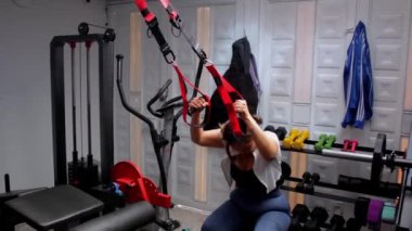 Spor salonu atletik kadın spor makinesinde bacak egzersizi yapıyor.