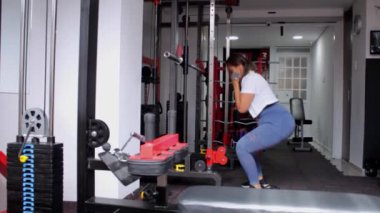 Spor salonu atletik kadın spor makinesinde bacak egzersizi yapıyor.