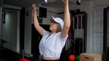 Spor salonunda spor yaparken spor makinesinde kol egzersizi yapan spor sporcusu bir kadın.