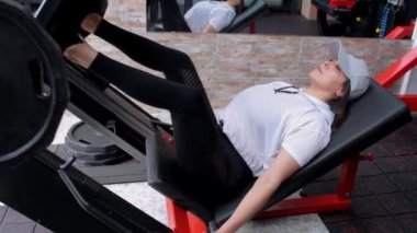 Spor salonundaki spor salonunda bacak ve kalça egzersizi yapan yetişkin bir kadın.