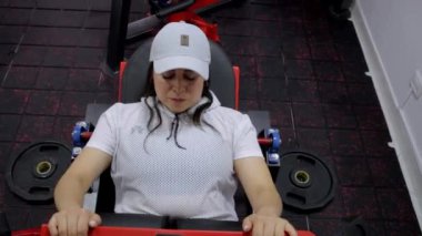 Spor salonundaki spor yapan yetişkin bir kadın spor aletinin ağırlığıyla karın egzersizi yapıyor.