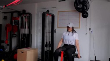 Spor salonu atletik kadın spor makinesinde bacak egzersizi yapıyor.