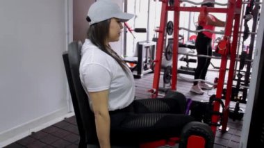 Spor salonu atletik kadın spor makinesinde bacak egzersizi yapıyor.