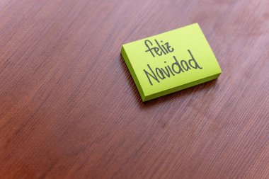 Ahşap masa arkasında yapışkan bir not. Yazılı not: Mutlu Noeller.