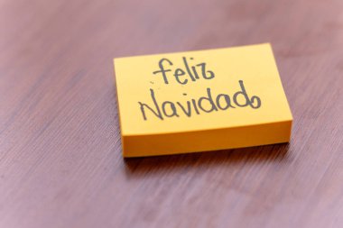 Ahşap masa arkasında yapışkan bir not. Yazılı not: Mutlu Noeller.