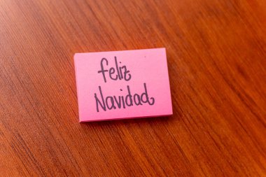 Ahşap masa arkasında yapışkan bir not. Yazılı not: Mutlu Noeller.