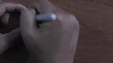 Bir insan masa tahtası arka planına yapışkan bir not yazıyor. Yazan kişi Mutlu Noeller diyor.