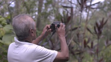 Dağdaki kıdemli doğa fotoğrafçısı - profesyonel film yapımcısı ormanda doğa videosu kaydediyor